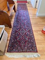 Full length photo of the dark red oriental runner rug with floral motif placed on hardwood floor.