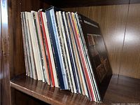 Side view of a shelf holding approximately 20 vinyl record albums showing spines and edges indicating vintage collection.