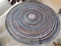 Full view of circular braided rug on carpeted floor