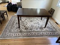 Full view of the rectangular rug laid out on hardwood floor under a dining table, showing overall size and design.