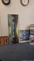 Photo showing original cityscape painting on canvas, two framed prints (children and street scene), and two Houston Harvest tins with farm images.