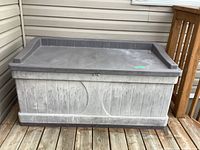 Full view of weathered large plastic deck box with textured lid and embossed Sun Cast logo, showing overall condition and dimensions.