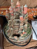 Castle-themed desk fountain with towers and rocky base, showing power cord attached and detailed paintwork.