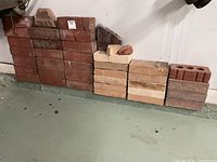 Wide view of several stacks of garden bricks in varying colors and styles, some broken pieces on top