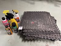 Stack of 22 black heavy duty interlocking garage floor mats with circular textured surface and interlocking tabs on edges.