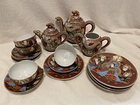 Full view of tea pot, creamer, sugar bowl, cups, plates and saucers arranged together.