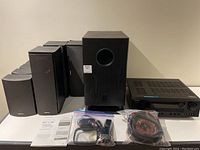 Photo showing the full set including subwoofer, multiple speakers, AV receiver, cables, remote, and manual.