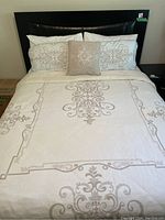 Front view of assembled queen bed showing headboard, mattress, sheets, duvet and pillow covers