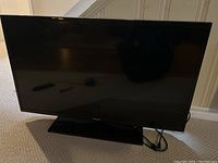 Samsung 40-inch smart TV front view showing the screen and stand on a carpeted floor.