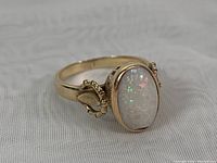 Front angled view of ring showing opal's play-of-color and gold band