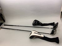 Two Cleveland driver golf clubs laid flat showing club heads and head covers.