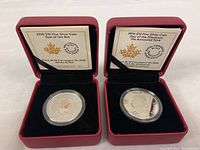 Two $10 silver collectible coins in red display boxes with information cards for 2020 Year of the Rat and 2016 Day of the Dinosaurs.