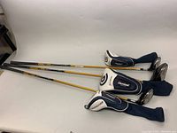 Full view of the three golf clubs laid out side by side showing club heads, shafts, and head covers.