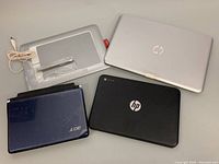 Photo showing all items together: two HP laptops, one Acer laptop, and one Wacom Bamboo tablet with stylus pen