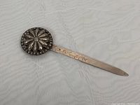 Full view of the 6 inch silver letter opener showing the floral round top and decorated shaft