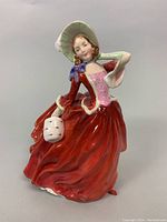 Front and side view of Royal Doulton Autumn Breezes porcelain figurine displaying details on dress, face, and basket.