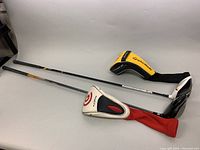 Photo showing both golf driver clubs with their respective head covers lying flat on a surface. The Cleveland Launcher has a white and red cover, and the TaylorMade has a black and yellow cover.