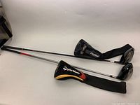 Full view of both golf clubs with headcovers showing clubheads and shafts