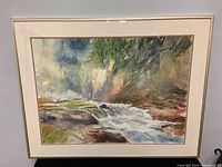 Full frontal photo of the framed watercolor painting showing the waterfall and river landscape with minor wear on the frame.