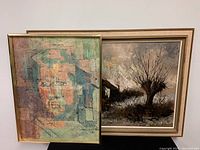 Photo showing both framed artworks together, the abstract portrait painting in front and the landscape print behind.