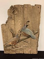 Full view of relief sculpture featuring two California Quail birds on wood-like panel with visible texture and plaque