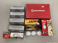 Photo of entire lot showing polishing cloth boxes, multiple golf ball boxes, golf tees in bag, and golf markers box.