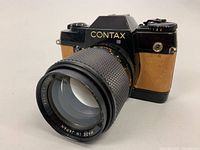 Front and angled view of CONTAX 137MA Quartz 35mm film camera body with attached Yashica 135mm f/2.8 lens showing CONTAX branding and lens details.