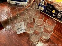 Photo showing the 15 clear Libbey Adobe glasses arranged on a wooden surface.