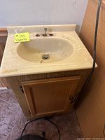 Photo of wooden bathroom vanity with beige marble-like countertop and integrated sink, showing condition and design.