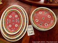 Overhead view of oval and round plates showing red pattern and border