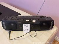 Full front view of black Citizen Surround X-88 stereo boombox radio showing speakers, control buttons, and power cord plugged in.