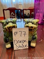 Pair of green and white ceramic dragon statues on a table with a note indicating lot number 27
