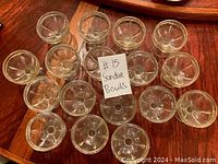 Top view of 17 clear glass sundae bowls arranged in a circle showing the interior flower-like pattern and round base.