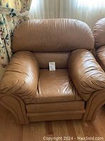 Brown leather armchair with plush cushions and soft padded arms, no visible damage.