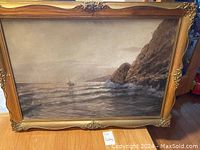 Full view of painting showing sailboat on sea near rocky shore with detailed frame.