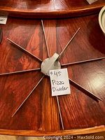 Metal pizza divider with eight cutting arms radiating from central hub on wooden surface, with a label reading '#45 Pizza Divider'