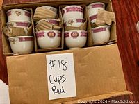 Box containing 12 porcelain tea cups with red pattern, some cushioned with cardboard separators.