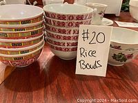 Rice bowls stacked on wood surface, showing red patterned glass bowls and colorful patterned plastic bowls.