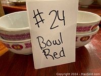 Close-up of four stacked rice bowls showing red and gold decorative bands with a card reading '#24 Bowl Red'