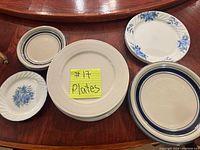 Photo showing 6 small and 13 large plates in various white, beige, and blue tones with different floral and ring patterns.