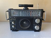 Full front view of vintage Venturer Multiband Radio showing speaker, tuning dials, battery meter and telescoping antenna.