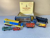 Full view of the collectible toy vehicles arranged outside an open vintage cigar box with label 'Bances Imported Habana Corona Deluxe Claro'.