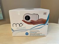 Front view of the ME Smooth by Iluminage retail box showing the device in a hand and branding information.