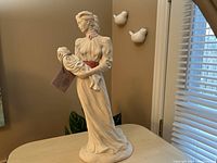 Front angled view of the sculpture showing the mother holding the baby, displayed on a table in natural light.