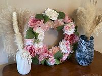Photo showing the peony wreath in the center with white ceramic vase containing dried pampas on the left and blue marbled glass vase with dried pampas on the right