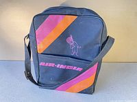 Front of vintage Air India carry-on bag showing logo and pink/orange stripes with Maharajah mascot