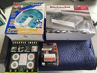 Photo of entire lot showing Dr. Scholl's Comfort Plus foot spa, KitchenAid dish rack 3-piece set, Sharper Image LED puck light set and Kidde Pro65 smoke alarm