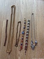 Full lot including assorted bracelets and necklaces arranged side by side on wooden surface.