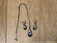 Photo showing necklace and earrings laid flat on wood surface.