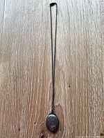 Full view of the sterling silver locket necklace laid flat on a wooden surface showing overall length and chain.